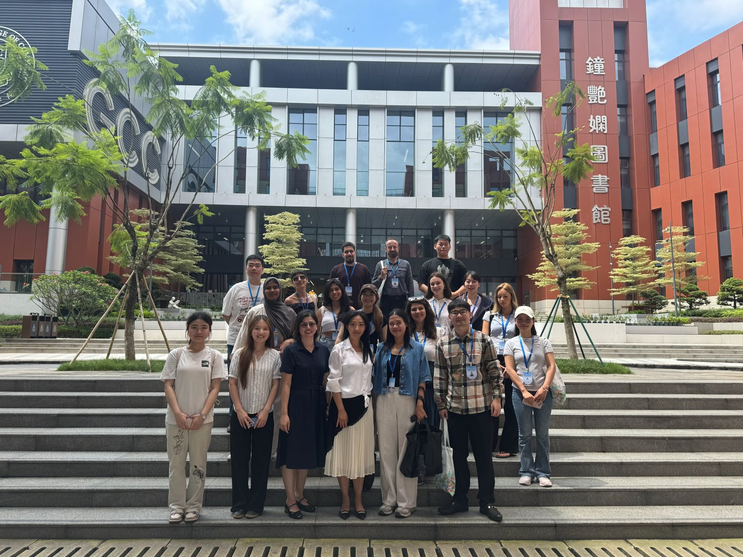全体成员在广商图书馆的台阶上合影，红橙相间的楼宇，两旁棕榈相衬。